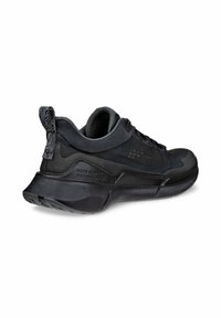 Svarta träningsskor med en texturerad mesh-överkonstruktion, dämpad sula och en mönstrad dragflik vid hälen för enkel påtagning.