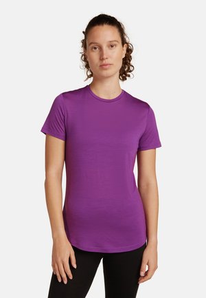T-shirt viola a maniche corte con scollo rotondo, texture liscia e orlo leggermente curvato, abbinato a leggings neri.