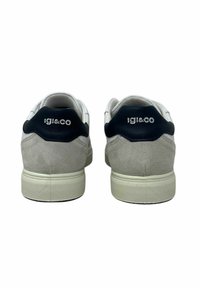 Sneaker bianchi e grigi realizzati in materiali scamosciati e in pelle, con un tacco posteriore blu navy, suola in gomma testurizzata e logo impresso sul retro.