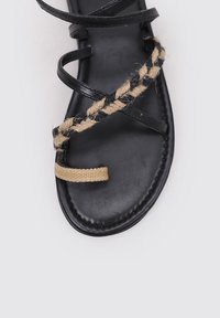 Sandalia de cuero negro con acentos de fibra natural trenzada; cuenta con suela plana y múltiples correas cruzadas para un ajuste seguro.