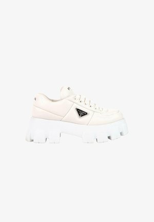 Baskets en cuir blanc Prada avec semelle épaisse rainurée, lacets à l’avant et plaque triangulaire noire du logo sur le côté.