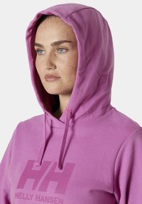 Sudadera con capucha rosa y cordones; presenta un gran logo "HH" en el pecho. Tejido suave con una textura lisa y un corte holgado.