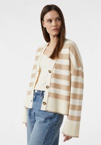 Pasek kardigan w beżowo-kremowe pasy, o luźnym kroju, zapinany na guziki, z szerokimi ściągaczami na rękawach. Stworzony do stylizacji z jednolitym topem na ramiączkach i dżinsami.