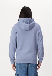 Felpa con cappuccio azzurro chiaro realizzata in tessuto morbido, con vestibilità rilassata, maniche lunghe e cappuccio a doppio strato.