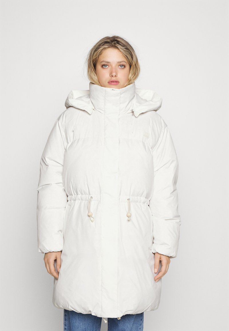 Abrigo tipo puff blanco con cuello alto, cinturilla ajustable con cordón y gran capucha. Presenta una textura suave y brillante y un detailing mínimo.