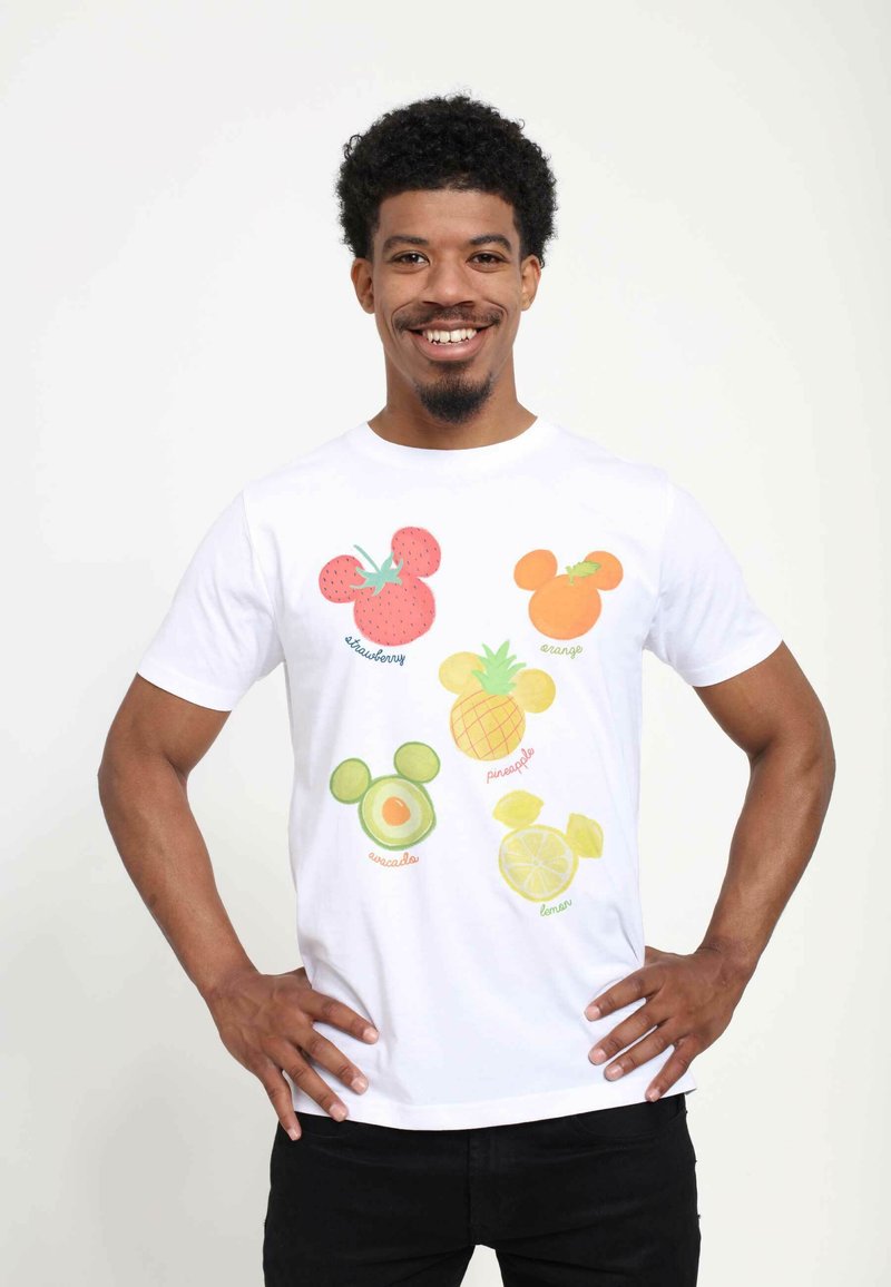 Vit bomull t-shirt med färgglada fruktgrafik som liknar Mickey Mouse: jordgubbe, apelsin, avocado, ananas, citron, med textetiketter.