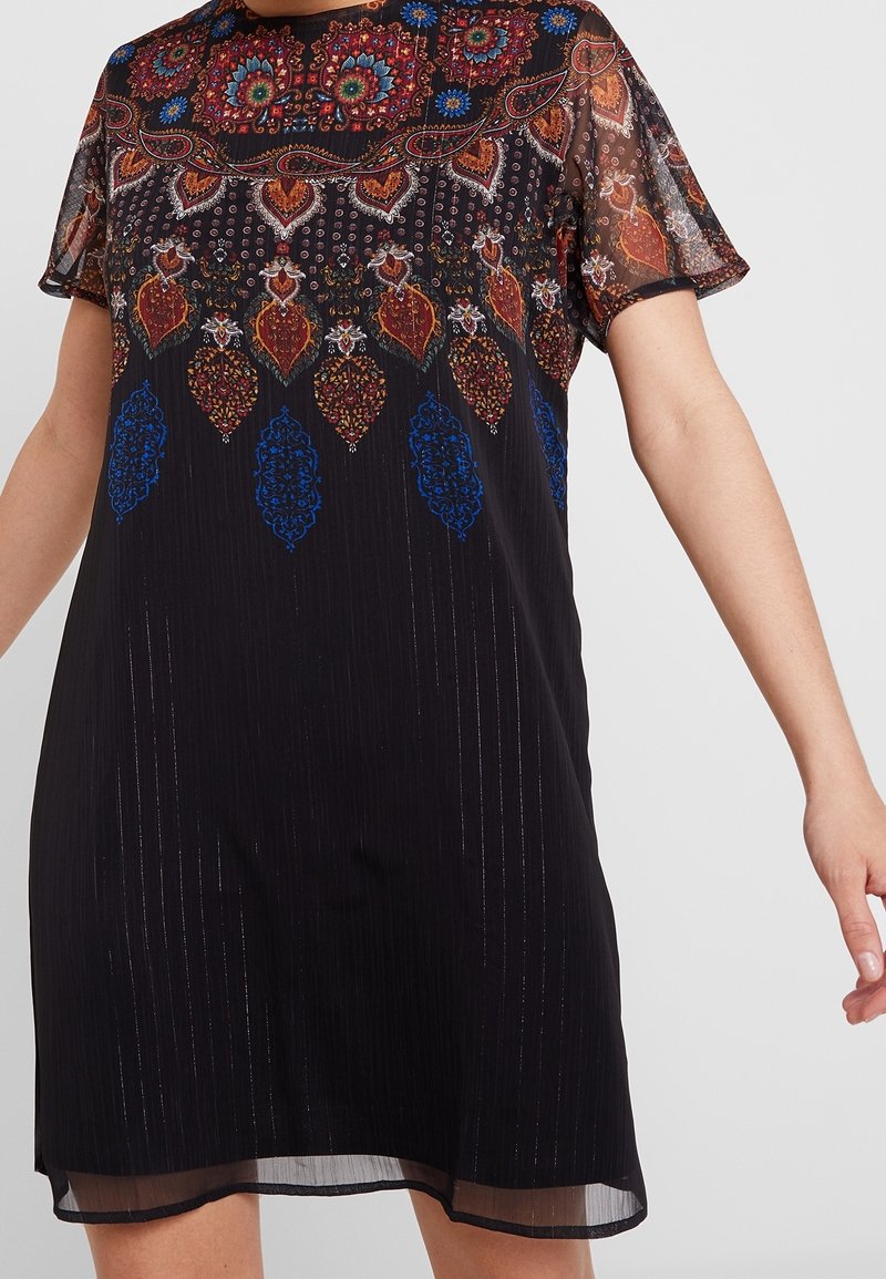 Robe courte noire avec des manches transparentes, motif floral et géométrique multicolore complexe autour de l'encolure et du haut de la poitrine.