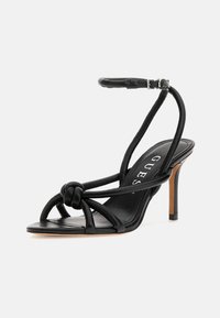 Musta korkokenkäsandaali, jossa on solmittu etuosan muotoilu, ohut nilkkaremmi ja sileä nahkapinta. Varustettu hoikalla stiletto-korolla.