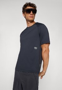 Dark blue athletic t-shirt with short sleeves, seamless design, logo on the front, paired with matching shorts, smooth texture.