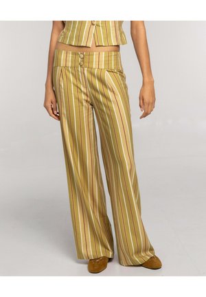 Pantalones de pierna ancha con rayas verticales en amarillo y marrón, cintura con doble botón, combinados con top corto a juego y zapatos marrones.