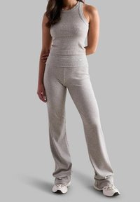 Szary ribbed top na ramiączkach i dopasowane spodnie wykonane z teksturowanej tkaniny. Strój charakteryzuje się dopasowanym krojem i szerokim pasem, dopełniony białymi butami.