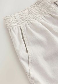 Lichtgrijze shorts met een elastische tailleband, zijzakken en een zachte, gestructureerde stof. Kenmerkt nette stiksels langs de naden.