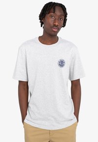 Graues T-Shirt aus Baumwolle mit kurzen Ärmeln und rundem Halsausschnitt, mit einem kreisförmigen grafischen Logo in Marineblau auf der linken Brustseite.