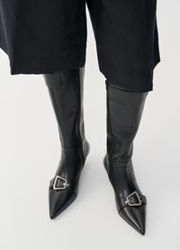 Black leather knee-high boots with a pointed toe and silver buckle accent. Features a zipper on the inner side and smooth texture.