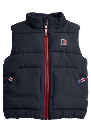 Veste sans manches matelassée bleu marine avec col montant, fermeture éclair rouge, deux poches avant, et accents rayés colorés sur les poches. Comprend un écusson logo.