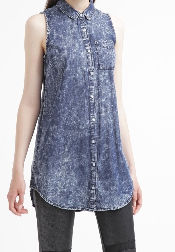 Camicia senza maniche in denim, azzurro chiaro con lavaggio sbiadito, chiusura frontale con bottoni, colletto e taschino singolo sul petto. Orlo curvo nella parte inferiore.