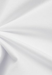 Il tessuto di cotone bianco presenta una superficie liscia con una sottile lucentezza, drappeggiandosi in morbide pieghe che evidenziano la sua leggerezza e traspirabilità.
