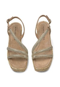 Sandales slingback beiges avec des brides croisées métalliques et tissées. Texture en daim douce, semelle enveloppée de jute et bride de cheville réglable.