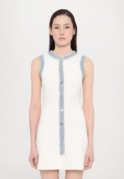Robe blanche sans manches avec bord en denim, présentant un devant à boutons et un ourlet plissé. Le tissu a une texture lisse avec un léger éclat.