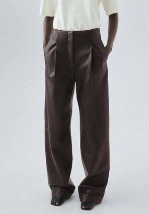 Pantalones de talle alto y pernera ancha en marrón oscuro, confeccionados en una tela suave con pliegues en la parte delantera y bolsillos laterales, combinados con una blusa blanca.
