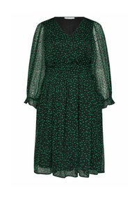Svart klänning med gröna prickar, v-ringad halslinje, långa genomskinliga ärmar, smockad midja och veckad kjol, tillverkad av lätt och genomskinligt material.