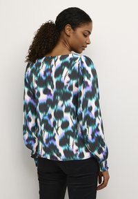 Langærmet bluse med et multikolonet, abstrakt mønster i teal, sort og lilla på en hvid baggrund. Glat stof med en rund halsudskæring.