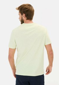 Bleg grön kortærmet t-shirt med rund hals og en afslappet pasform. Blød tekstur med subtile lyse variationer. Bagudsigt viser minimale detaljer.