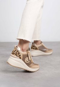 Zapatillas beige y marrón claro con un acento de estampado de leopardo, paneles de malla, cierre con cremallera y una suela de plataforma blanca gruesa. Detalles texturizados a lo largo.