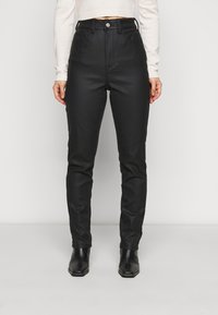 Pantalones negros de cintura alta hechos de una tela suave y texturizada, con bolsillos frontales, un cierre de botón metálico y un ajuste entallado a lo largo de las piernas.