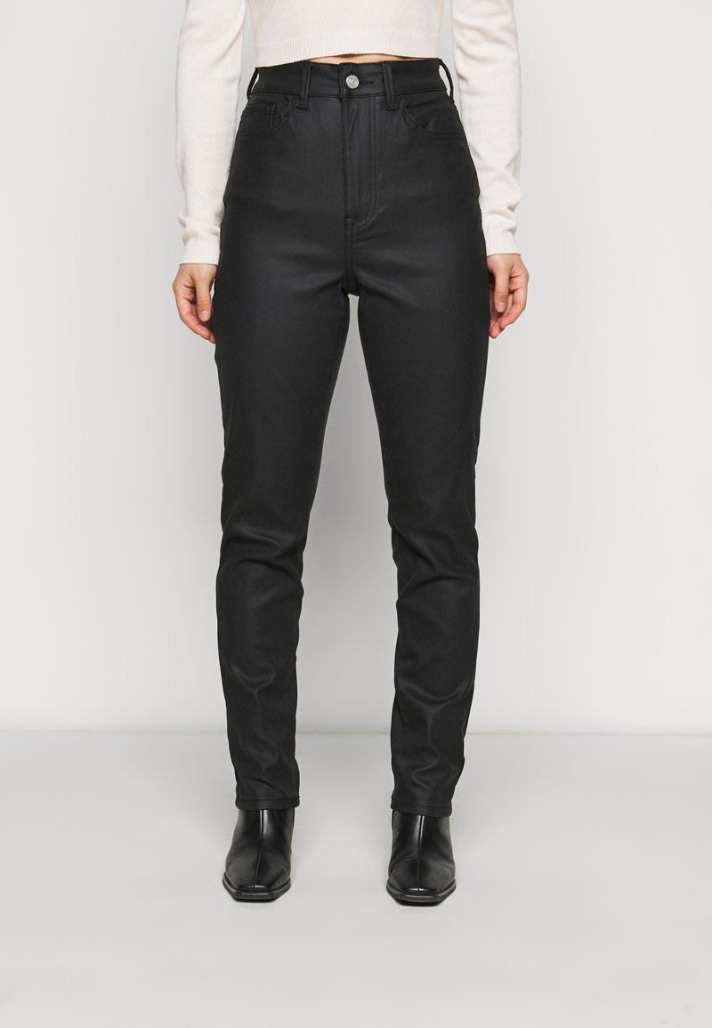 Pantalones negros de cintura alta hechos de una tela suave y texturizada, con bolsillos frontales, un cierre de botón metálico y un ajuste entallado a lo largo de las piernas.