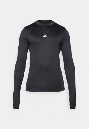 Long-sleeve athletic shirt in black, featuring a slim fit, crew neckline, and a white Adidas logo on the chest. Smooth, stretchy fabric.