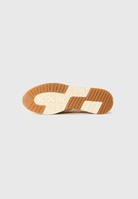 Sålen til en sneakers, med et mønstret design som kombinerer lys beige gummi og kremfarget mellomsåle. Strukturert grep for bedre feste.