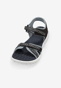 Sandale noire et grise avec des brides entrecroisées, semelle texturée, talon ajustable et accents à motifs. Fabriquée en matériaux synthétiques légers.