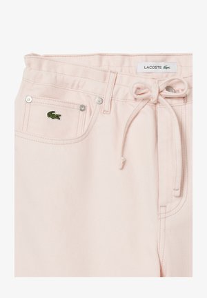 Heledad roosa denim lühikesed püksid, millel on paela talje, hõbedased detailid ja väike roheline Lacoste krokodillilogoga esi-taskus.