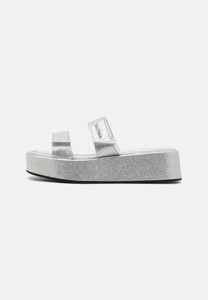Sølvglitrende platform sandaler med to brede stropper. Har en tyk sål med tekstureret finish og diskret branding på siden.