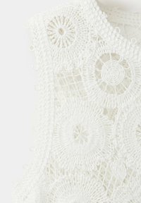 Tissu en crochet blanc avec des motifs floraux circulaires et des détails en maille, mettant en valeur une dentelle tissée à la main complexe et une texture délicate.