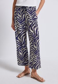 Loose-fit, purple pants with a white zebra print pattern, crafted from lightweight fabric. Features an elastic waistband with a drawstring.