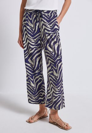 Pantaloni larghi viola con una stampa a righe zebra bianca, realizzati in tessuto leggero. Presentano una vita elastica con cordoncino.