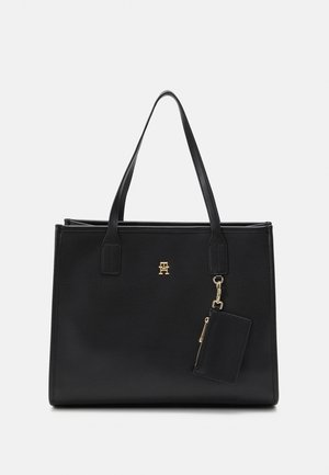 Schwarze Leder-Tote mit goldenen Akzenten, strukturierte Form, doppelte Henkel und abnehmbarer Kartenhalter. Mit Logo-Prägung auf der Vorderseite.