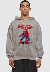Szürke kapucnis pulóver, amelyen egy nagy, piros és kék Spider-Man grafika látható, a kép felett pedig a "The Amazing Spider-Man" felirat olvasható. Puha tapintású.