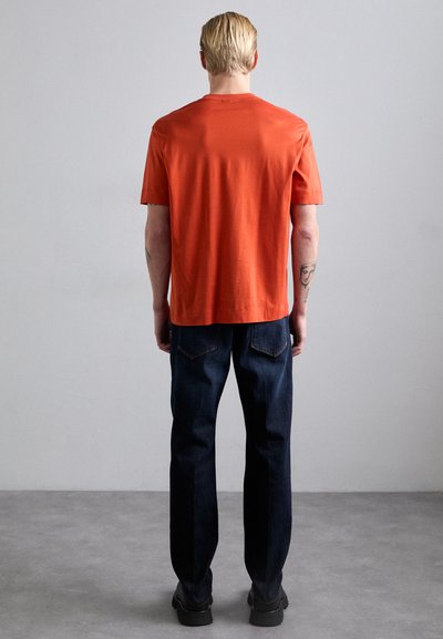 Short-sleeve orange t-shirt made of cotton, paired with dark blue denim jeans. Simple design, regular fit, and minimal detailing on both.
