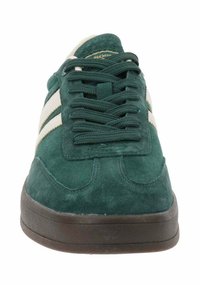 Sneaker verde in suede con strisce bianche, punta rotonda, suola piatta e lacci coordinati. La linguetta testurizzata presenta un dettaglio di branding.