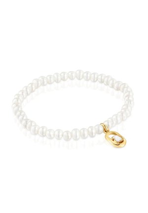 Braccialetto elastico di piccole perle bianche irregolari con un piccolo ciondolo ovale in oro decorato con un trifoglio bianco.