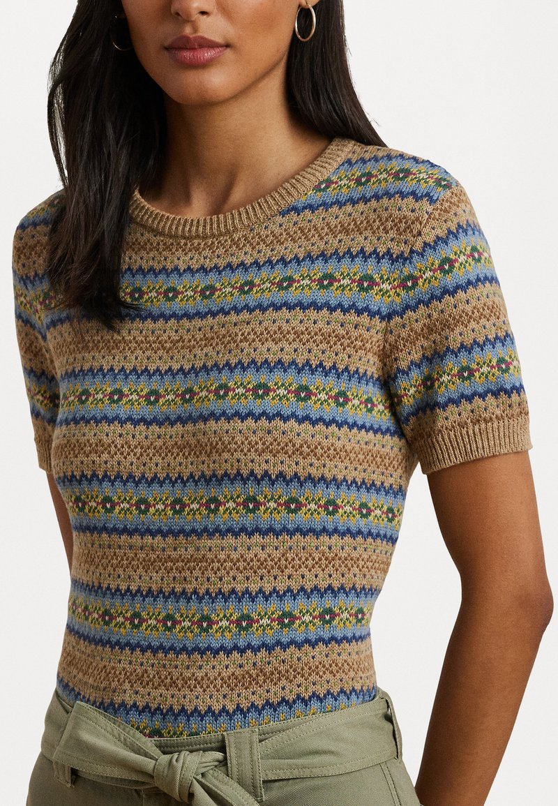 El suéter de punto presenta una base beige con patrones de rayas en azul, verde y amarillo. Mangas cortas y un escote redondo. Acabado texturizado.