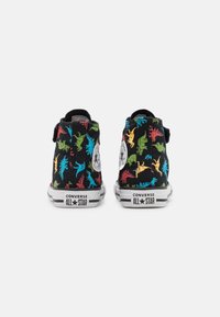 Svarta canvas hög-top sneakers med färgglada dinosaurmönster, vita gummisulor och Converse All Star-logotypen på sidan.