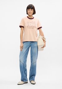 Ροζ μπλούζα με στρογγυλή μαραντίνα κολαρίτσα, με γραφικά σχέδια. Συνδυάζεται με ανοιχτό μπλε φαρδιά τζιν και λευκά slip-on παπούτσια.
