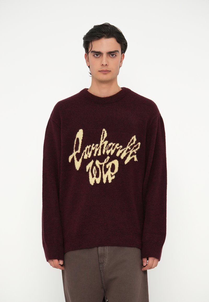 Bordeaux gebreid sweater met een losse pasvorm en ribgebreide halslijn, voorzien van een groot beige logo in cursiefschrift aan de voorkant.