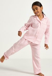 Lyserødternet pyjamas sæt med knap-op skjorte og lange bukser. Stoffet ser blødt ud med en løs pasform og en brystlomme på skjorten.