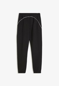 Črne trenirke z vrvico v pasu, zoženi hlačnici, elastičnimi manšeti in belim okrasnim šivom okoli bokov. Mehka tekstura tkanine.