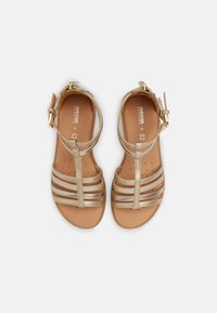GEOX szandálok fényes arany pántokkal, nyitott orrú kialakítással, párnázott talpbetéttel és állítható bokapánttal a biztos illeszkedés érdekében.